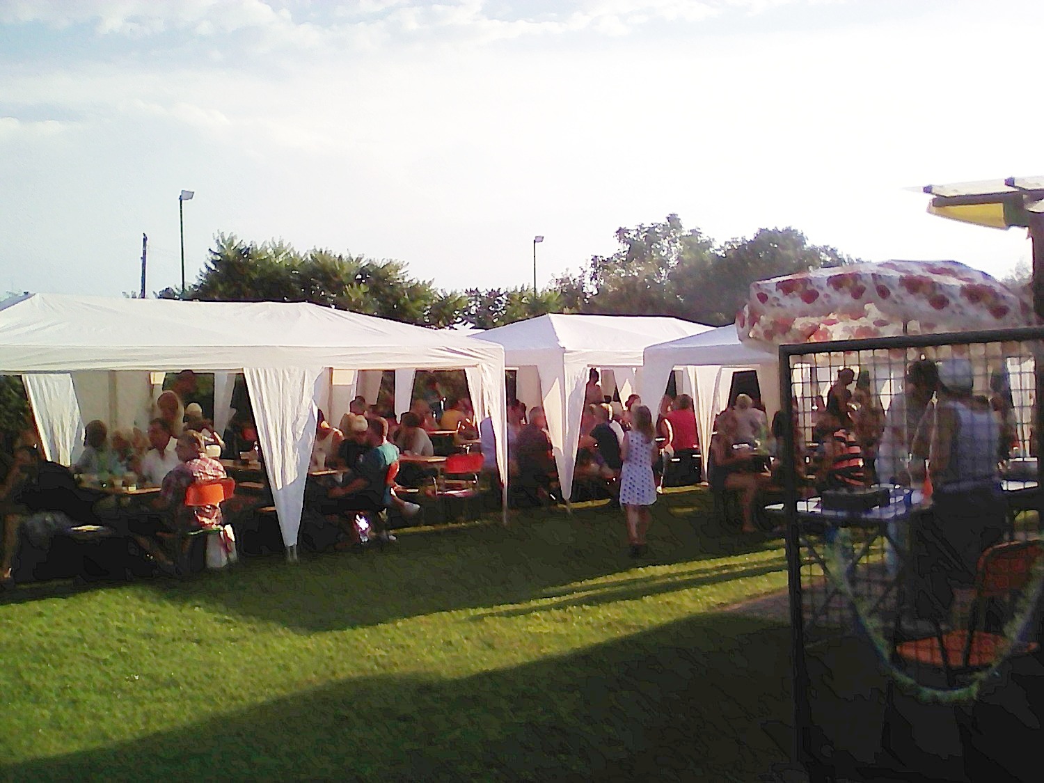 Der Vereinsplatz des Kleingartenvereins Biesenhorst II. Man sieht mehrere Zelte auf dem Rasen, unter denen zahlreiche Menschen an Tischen sitzen.